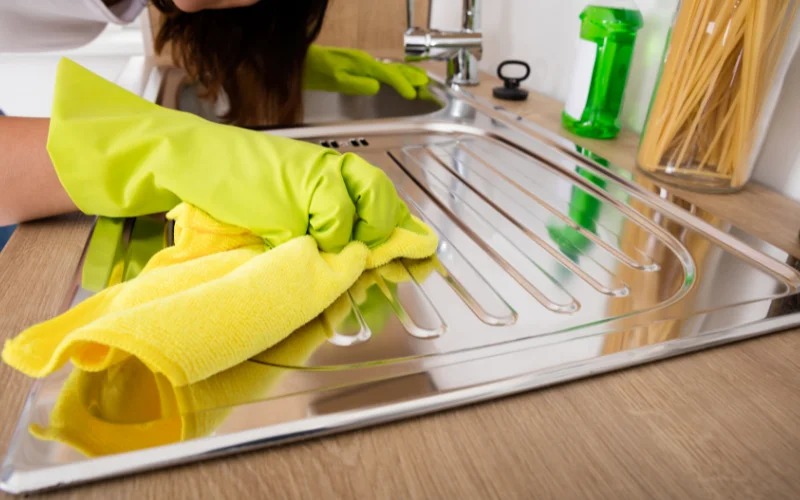 Ein Bild von einem glänzenden Edelstahltopf, der mit einem weichen Tuch und Essig poliert wird.